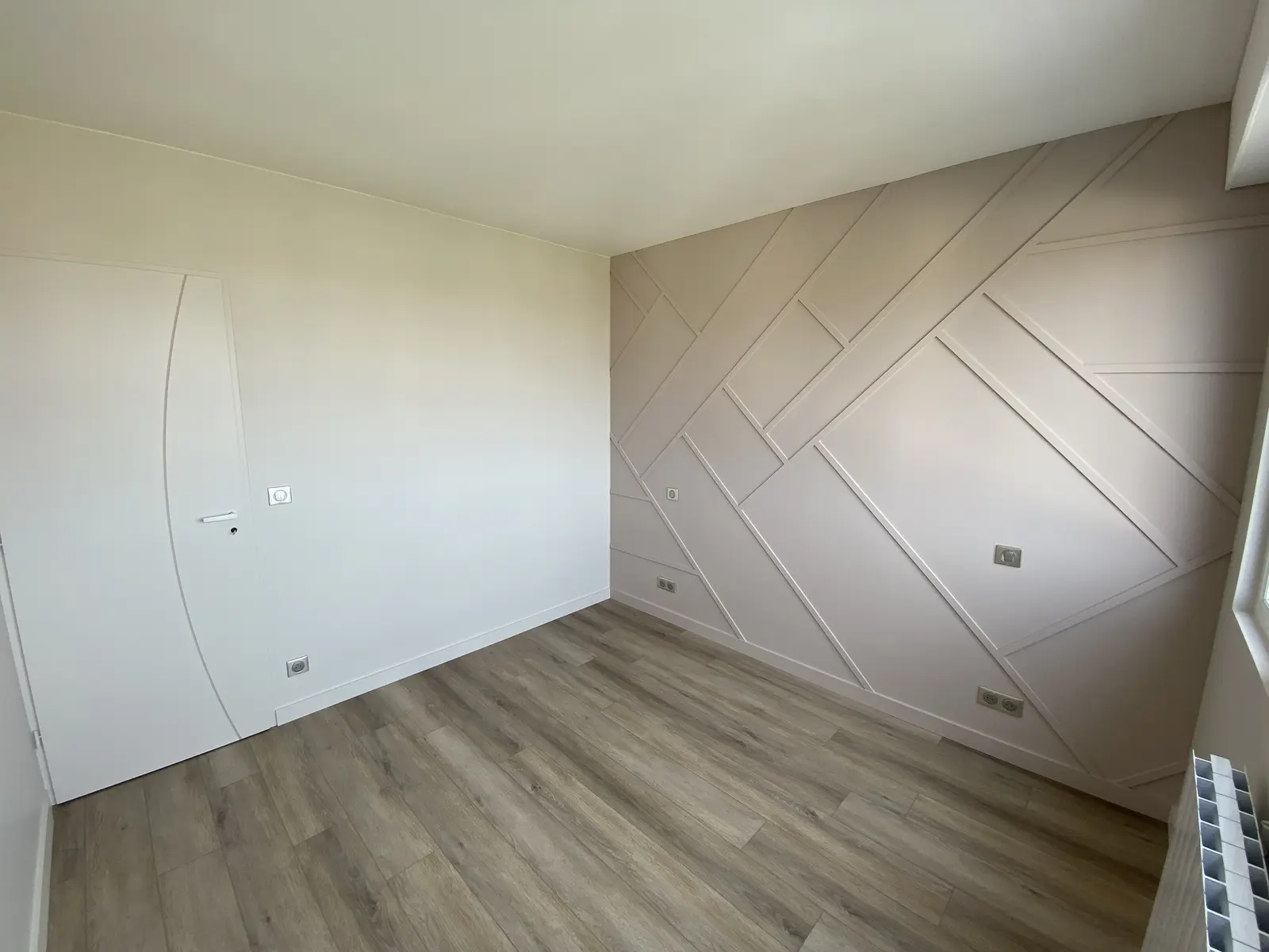 Chambre rénovée avec un mur en tasseaux peint en taupe, les autres murs en gris clair.