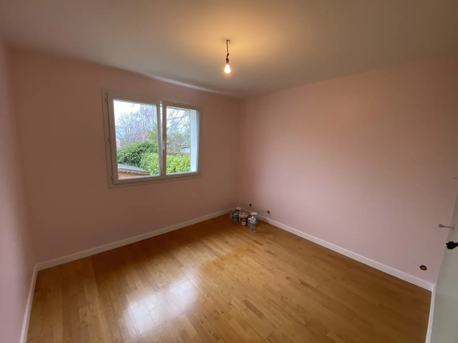 Chambre avec murs peints en rose, dont un mur d'accent peint en vert.