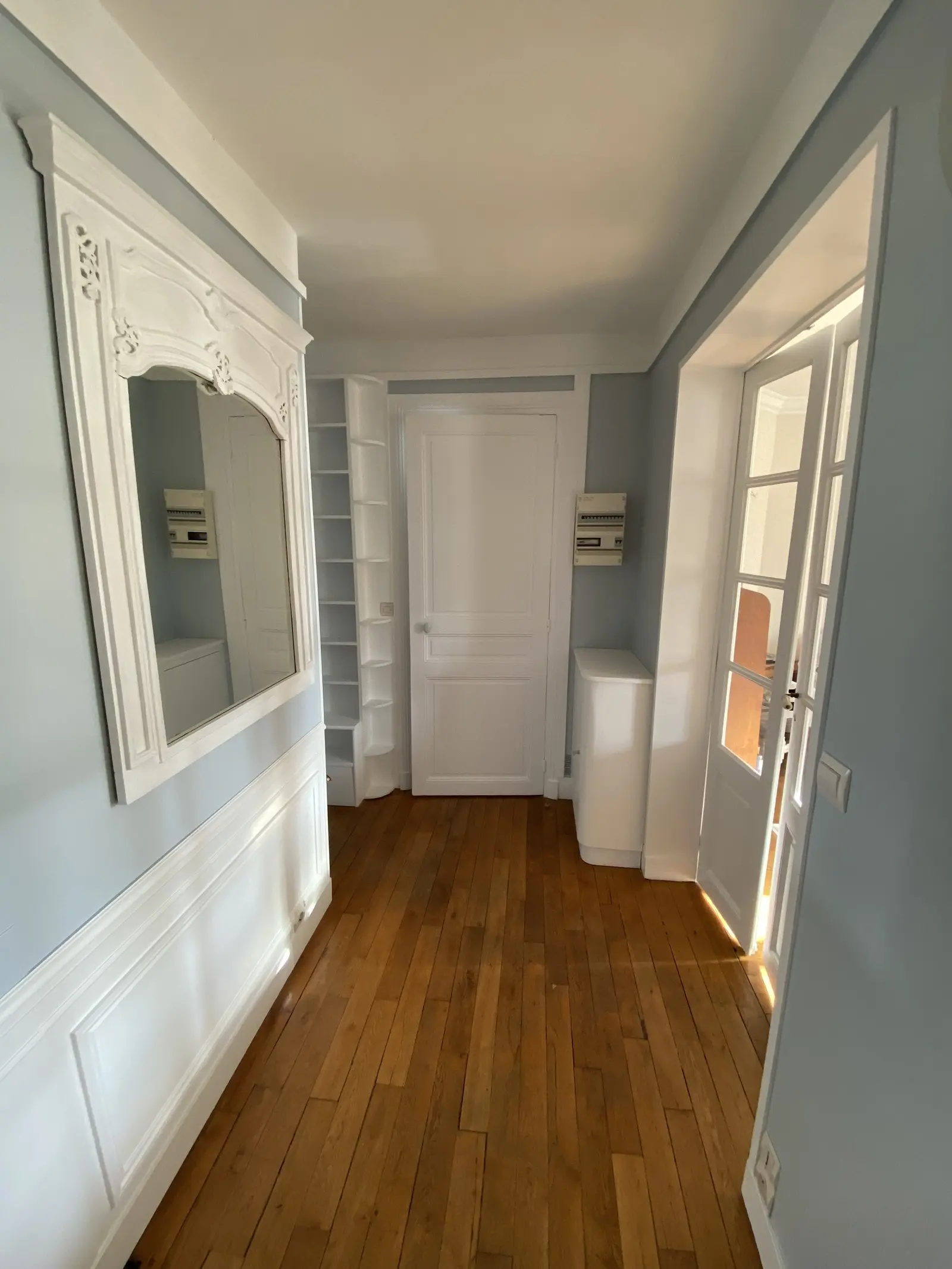 Couloir aux murs bleu-gris pâle avec moulures blanches, créant une ambiance élégante et sophistiquée grâce à des éléments de style classique.