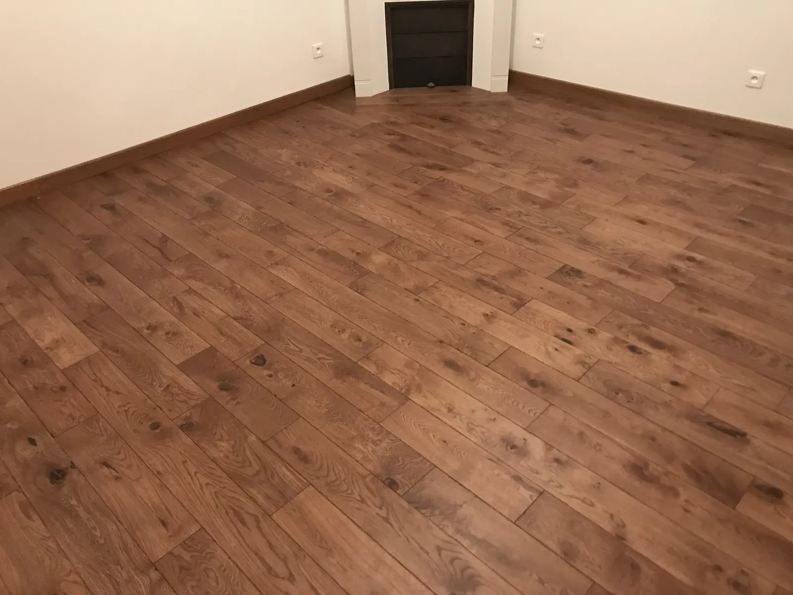 Sol en parquet collé, pose droite. Parquet brun au rendu élégant, chaleureux, avec des lames parfaitement alignées et une pose soignée.