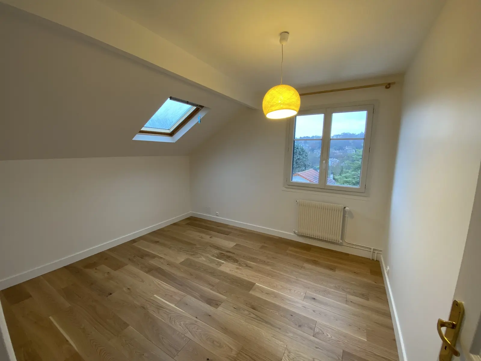 Sol en parquet flottant, bois clair. Pose droite soignée avec un alignement précis des lames, offrant une ambiance douce et moderne.