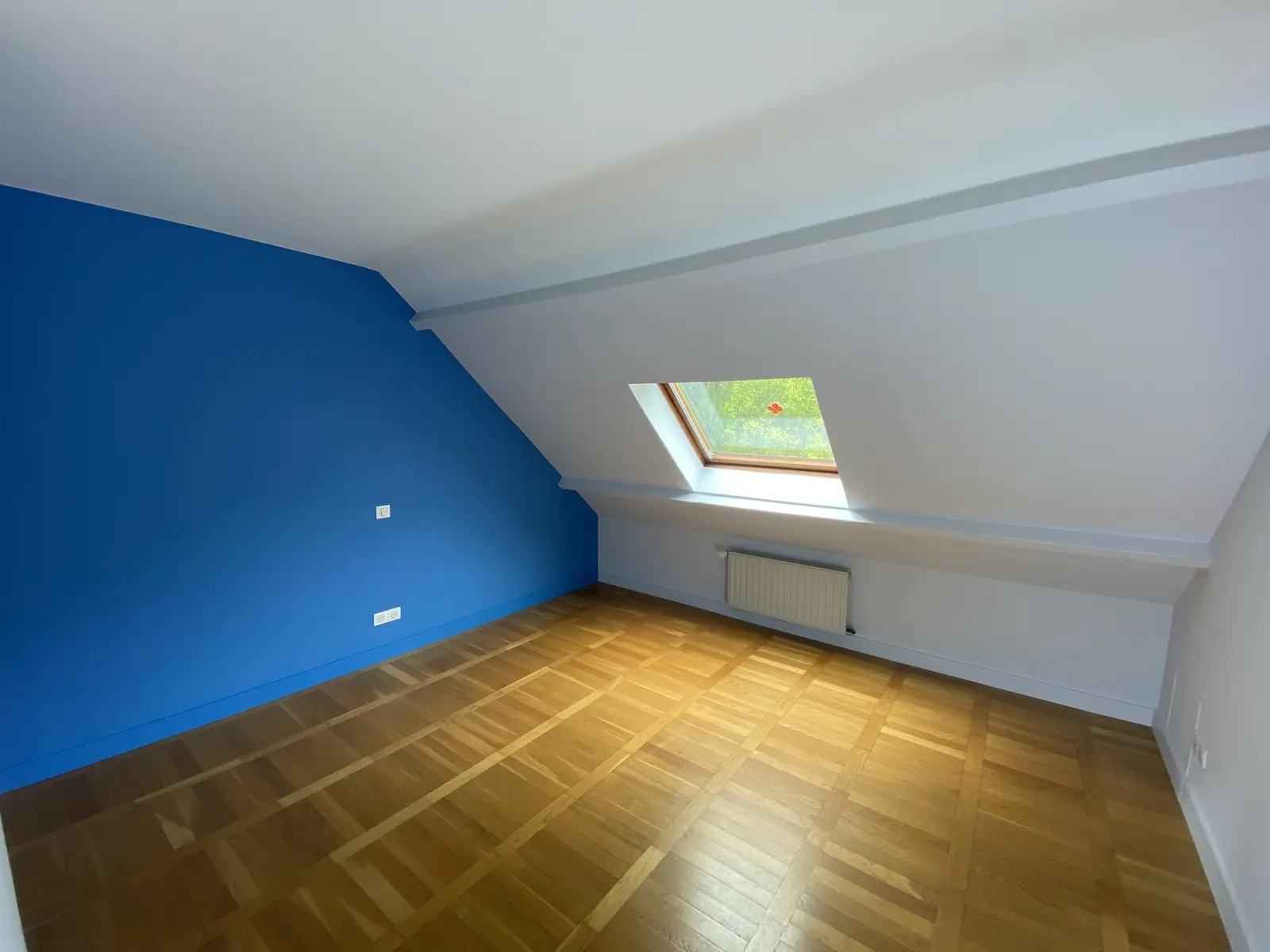 Chambre rénovée avec un mur bleu, en contraste avec les autres murs ainsi que les portes et encadrements peints en blanc.