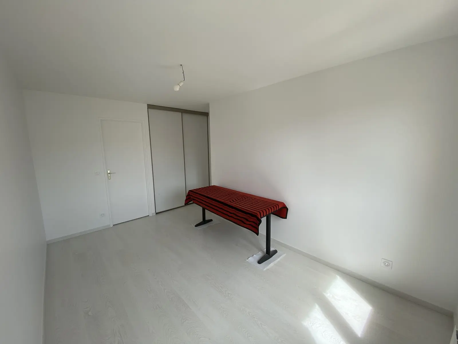 Intérieur lumineux aux murs blancs fraîchement peints, revêtement clair effet bois