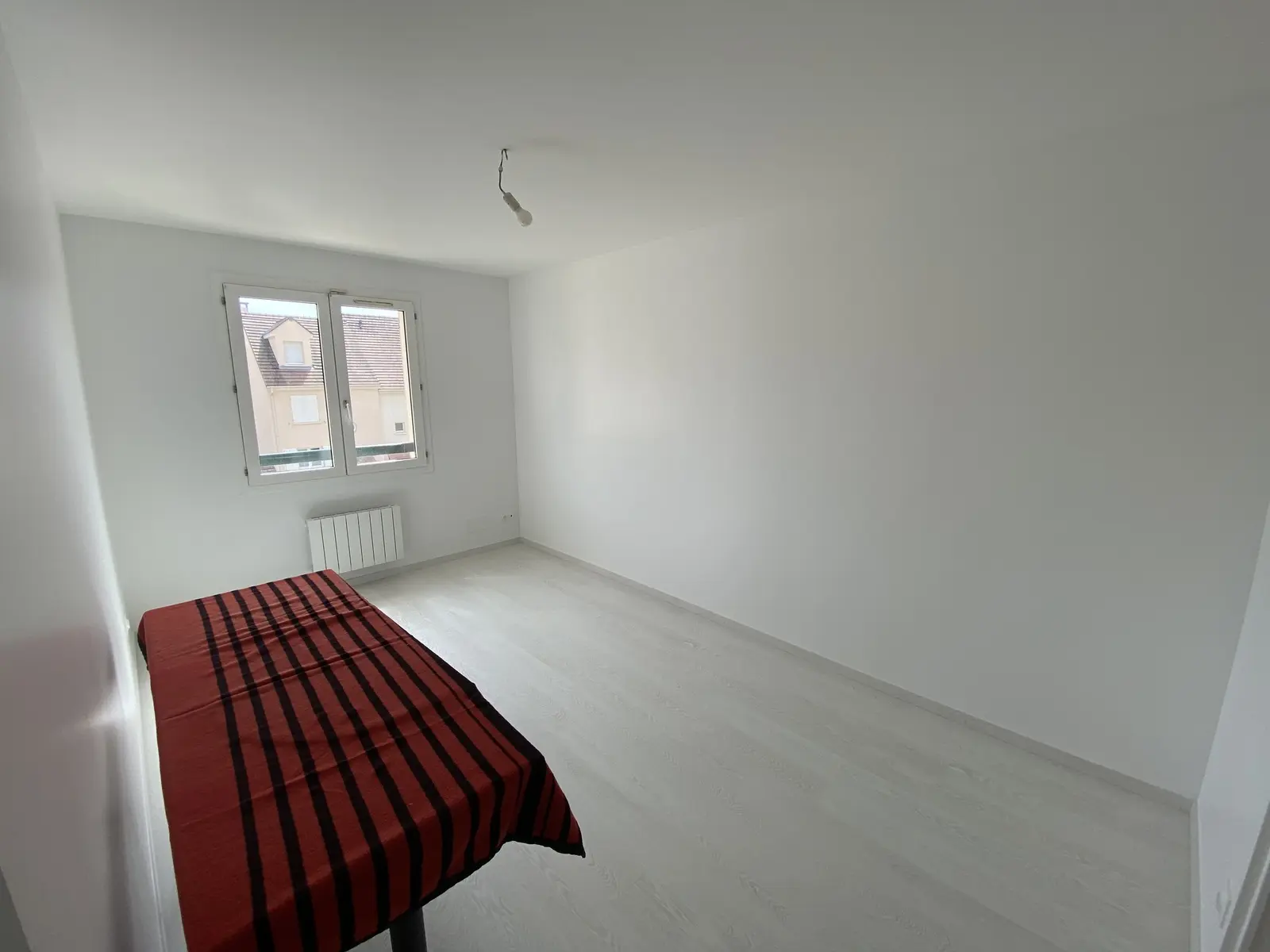 Pièce au style épuré, murs blancs fraîchement peints, revêtement clair effet bois